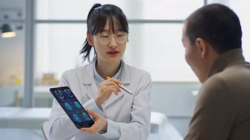 Asian Female Doctor Showing CT Scan on Tablet to Patient