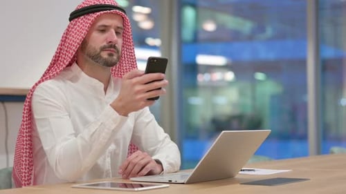 Man in Traditional Head Covering Using Smartphone in Office