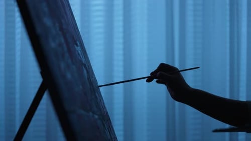 Artist Painting on Canvas with Brush in Dim Light