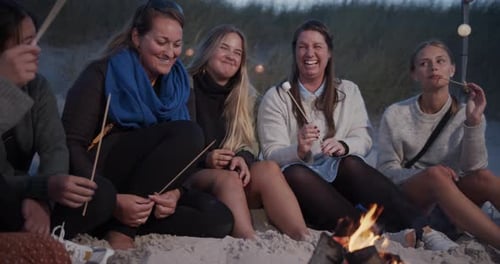 Magnifiques dames assises au bord de la plage autour du feu de camp