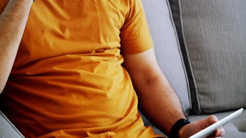 Young Adult Using Tablet and Smartphone on Couch