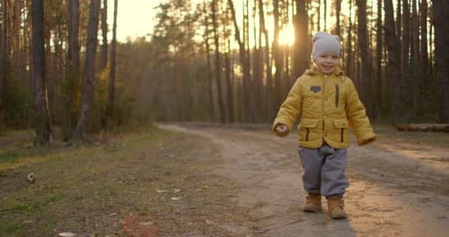 Slow Motion: Young Boy in a Yellow Jacket Explore the World Around Him While Sitting in the Forest