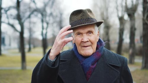 Senior Man Wearing Coat and Hat in City Park