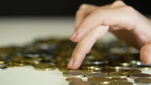 Hand Runs Finger Through Pile of Coins