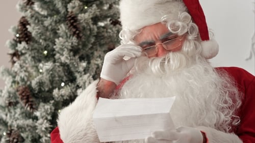 Santa Claus Reads Letter by Christmas Tree