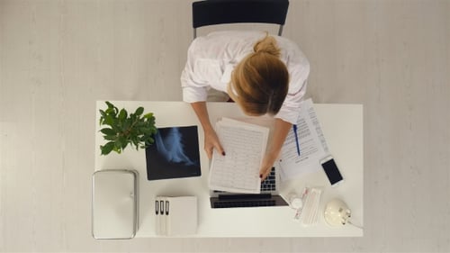 Young and Professional Doctor Working with Documents in the Medical Office.