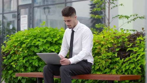 Young Man Using Tablet on Park Bench