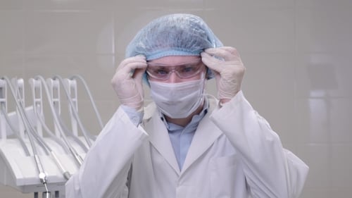 Man Doctor Surgeon in a Mask and Cap Stands in an Operating Room in Dental Clinic