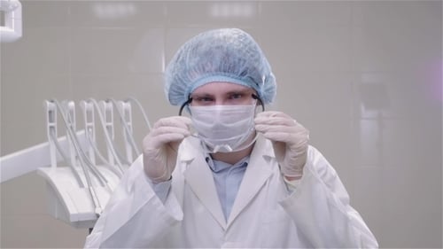 Young Doctor Puts on Protective Gear in Clinic
