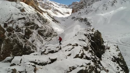 Hiker Walks Snowy Ridge in Mountain Landscape