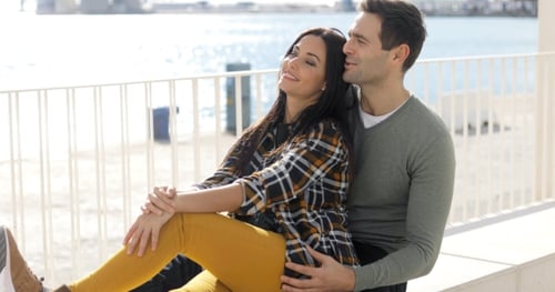 Affectionate Couple Sitting Together Near the Ocean