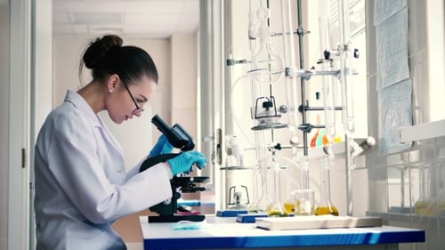 Woman Using Microscope in Bright Laboratory Setting