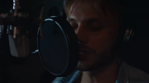 Young Man Singing Into Microphone in Studio