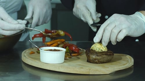 Chefs Preparing Steak Meal with Vegetables and Butter