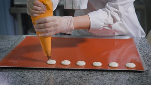 Baker Piping Macarons onto Baking Sheet