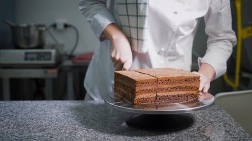 Kitchen. On a Table Ready Chocolate Cake. The Worker of a Candy Store in a White Special Form