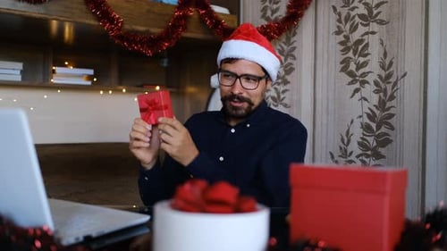 Close Up Portrait of Happy Caucasian Young Man in Santa Hat Sitting in Room