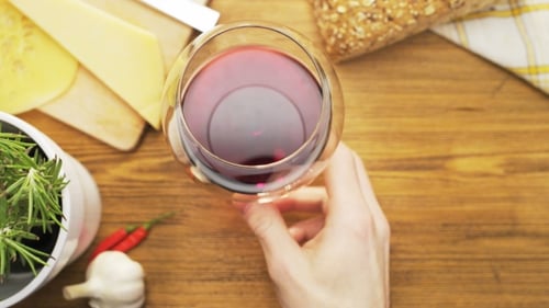 Hand Lifts Red Wine Glass Overhead