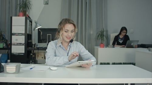 Fokussierte Callcenter-Agentin nutzt digitales Tablet an ihrem Arbeitsplatz