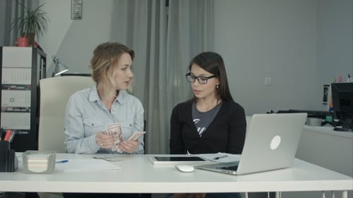 Women Talking at Desk Counting Money