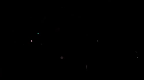Partikel fliegen auf schwarzem Hintergrund. Farbige Partikel fliegen unregelmäßig