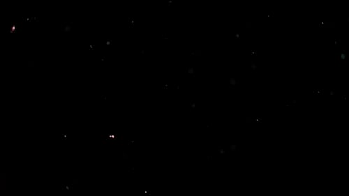 Partikel fliegen auf schwarzem Hintergrund. Farbige Partikel fliegen unregelmäßig.