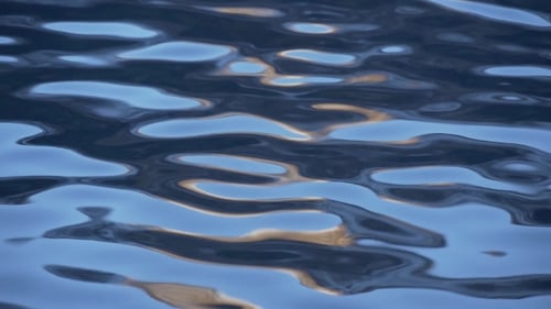 Gentle Waves on Water Surface with Gold Reflections