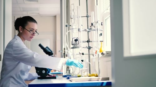 Woman Scientist Examines Liquid in Bright Lab
