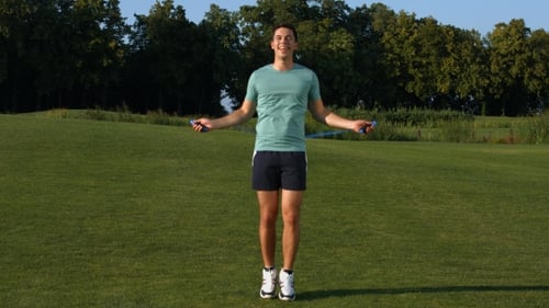 Guy Jumps on a Skipping Rope on a Green Meadow.