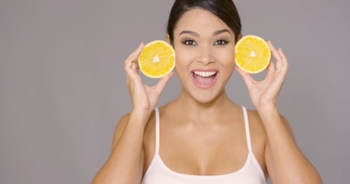Smiling Woman Holding Two Orange Halves