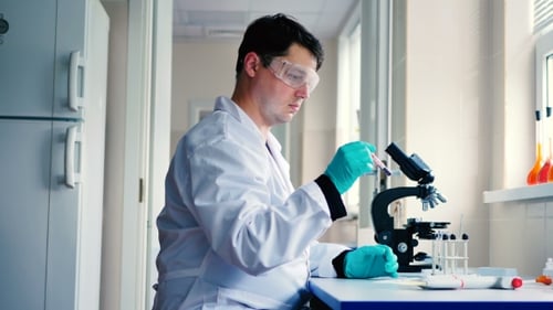 Scientist Working with Microscope and Test Tubes