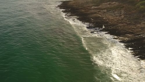 Ocean Waves Crashing on Rocky Shoreline From Above