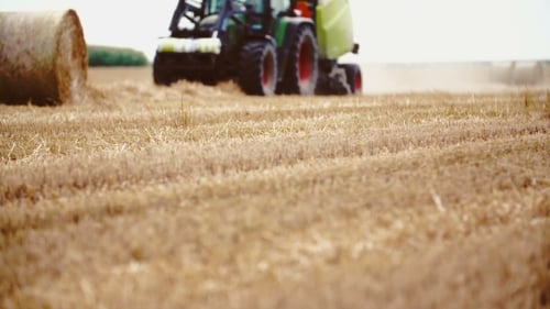Traktor gibt einen Heuballen und Stroh frei. Landwirtschaftlicher Hintergrund.