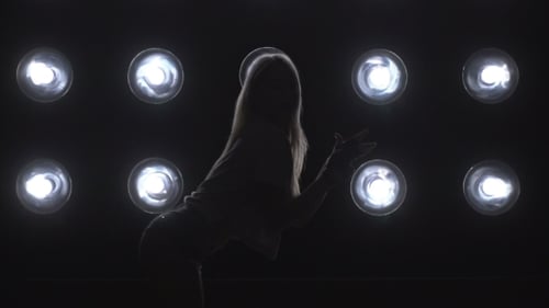 Silhouette eines Mädchens, das auf den Hintergrundlichtern tanzt.
