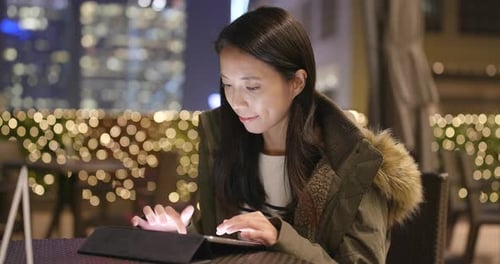 Woman Uses Tablet at Night in the City