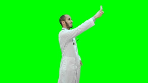 Smiling Doctor in White Coat with Stethoscope Taking Selfie on His Phone on a Green Screen, Chroma