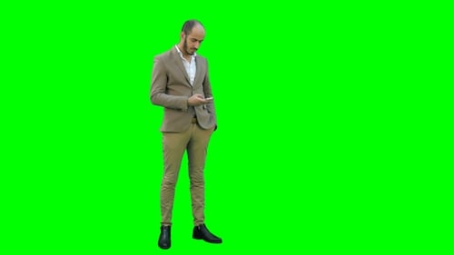 Young Man in Suit Sending Text Messages on His Phone on a Green Screen, Chroma Key.