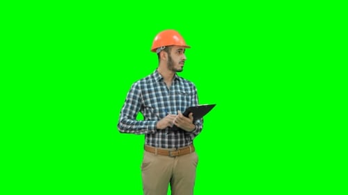 Young Engineer in Helmet Inspecting Construction Site on a Green Screen, Chroma Key.