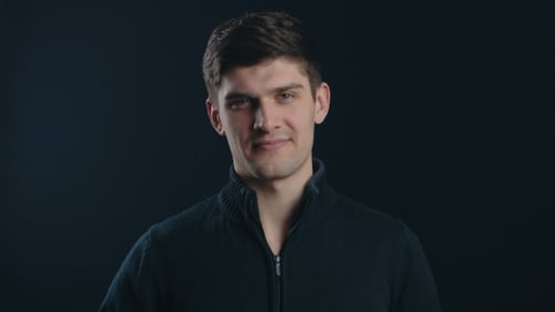 Man gestures no with raised finger on dark backdrop