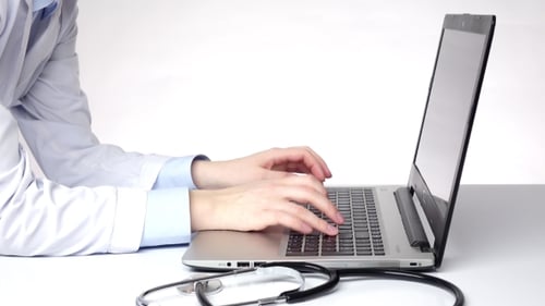 Doctor Using Laptop at Desk With Stethoscope