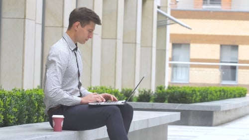 Man Working on Laptop Outdoors in Urban Setting