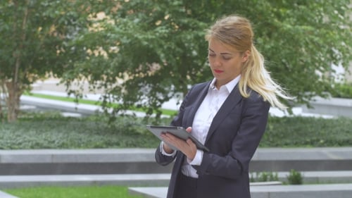 Woman with Tablet Computer Near Office Building.