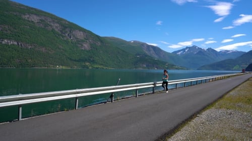 Woman Jogging on Rural Path by Lake on Sunny Day
