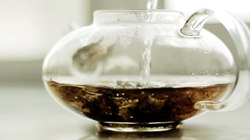 Water Pours Into Glass Teapot with Loose Leaf Tea