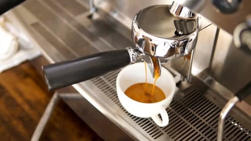 Espresso Streams Into White Cup on Machine