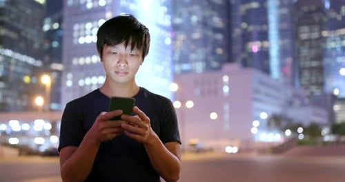 Man use of cellphone in city at night