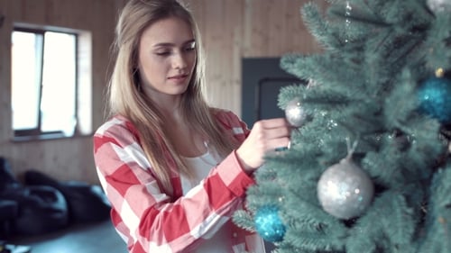 Woman Decorating Christmas Tree in Cozy Home