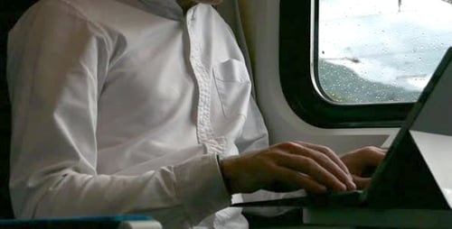 Man Working on Laptop on Train during Commute