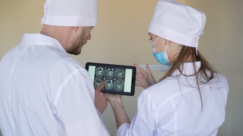 Male and Female Doctors Examine X-rays on the Tablet