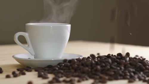 White Cup of Evaporating Coffee on Table Near Roasted Beans